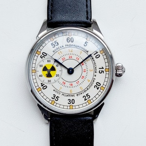 May include: A white watch face with black hands and a yellow and red radiation symbol. The watch face has black numbers and markings around the edge. The watch face reads "ВОЙСКА РАДИАЦИОННОЙ, ТИМИЧЕСКОЙ И БИОЛОГИЧЕСКОЙ ЗАЩИТЫ СССР".