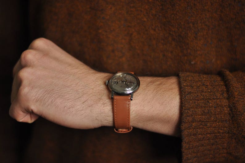 May include: A brown leather wristwatch with a silver face and a silver band.