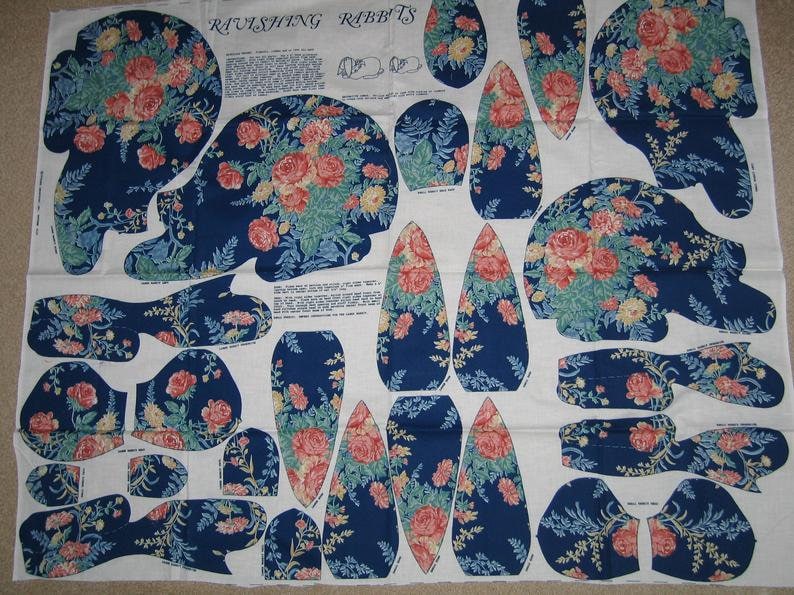 May include: A fabric pattern sheet with instructions for making a plush toy rabbit. The pattern pieces are printed on a white background with a blue floral design. The title of the pattern is "Ravishing Rabbits".