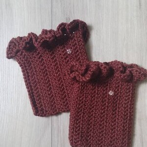 May include: A pair of maroon crocheted wrist warmers with a ruffled edge.