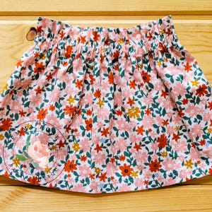 Op de afbeelding: Een witte keramische mok met een zwarte handgreep en de tekst "But First, Coffee" in een vetgedrukte, zwarte letter. De mok staat tegen een vage achtergrond, wat een gezellige setting suggereert.