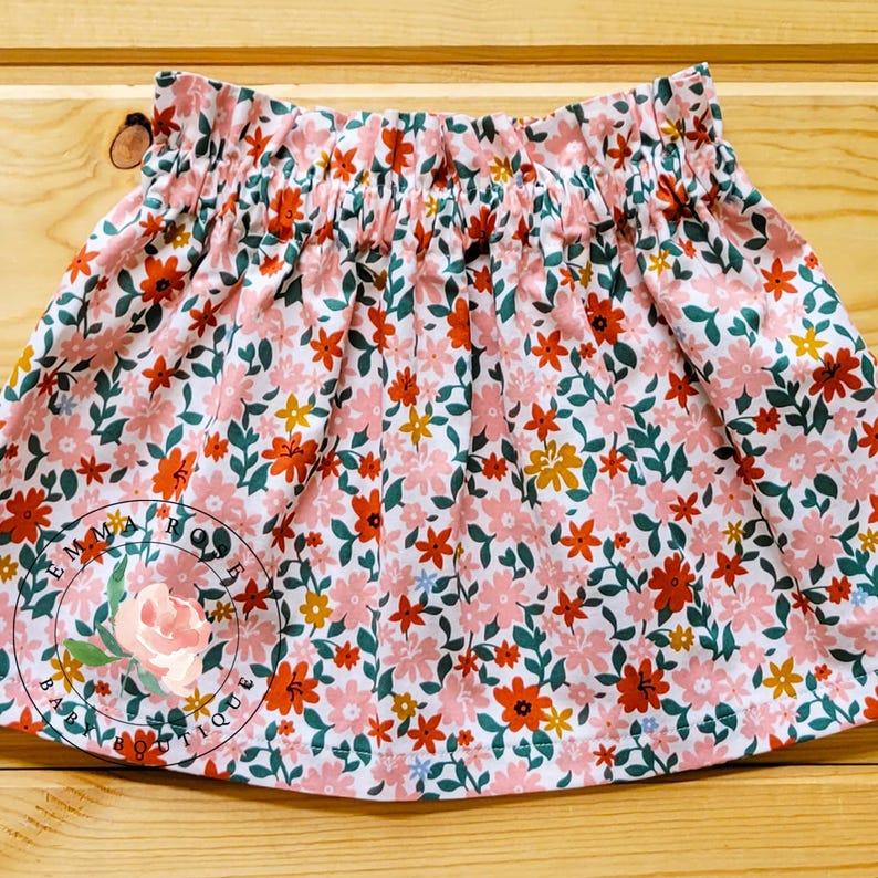 Op de afbeelding: Een witte keramische mok met een zwarte handgreep en de tekst "But First, Coffee" in een vetgedrukte, zwarte letter. De mok staat tegen een vage achtergrond, wat een gezellige setting suggereert.