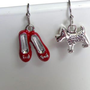 May include: A pair of dangle earrings. One earring features red, enameled ballet slippers with silver-tone accents. The other earring is a silver-tone charm of a dog.