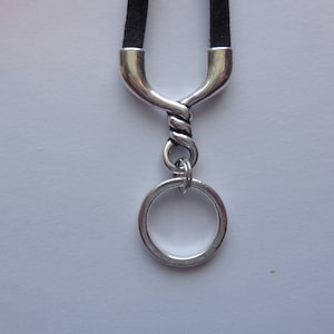 May include: A silver key chain with a twisted metal design and a round ring. The key chain is attached to a black cord.