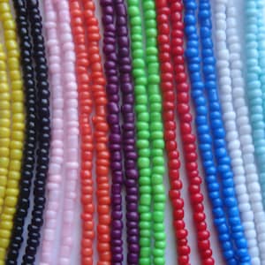 May include: A collection of 12 strands of colorful seed beads. The beads are arranged in a row and are all the same size. The colors of the beads are yellow, black, pink, orange, purple, green, red, blue, white, and light blue.