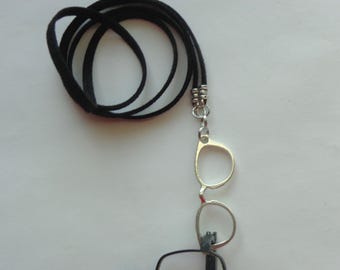 May include: A black cord eyeglass holder with a silver-toned metal glasses frame. The cord is looped and connected to the frame with a small silver chain and decorative beads. The glasses frame is empty.