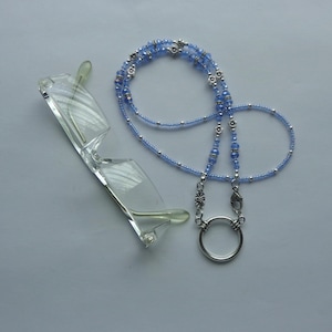 May include: A light blue beaded eyeglass chain with silver accents and a silver clasp. The chain is made of small beads and has a delicate look.