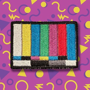 May include: Embroidered patch featuring a colorful television test pattern. The patch has a black border and includes vertical bars of white, yellow, green, magenta, and red. The background is a purple pattern with geometric shapes.