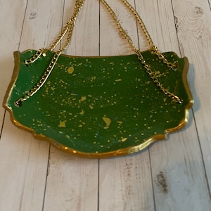 K&ouml;nnte beinhalten: Ein gr&uuml;nes und goldenes Dekotablett mit einer goldenen Kette zum Aufh&auml;ngen. Das Tablett hat eine gesprenkelte gr&uuml;ne Oberfl&auml;che mit goldenen Flocken.