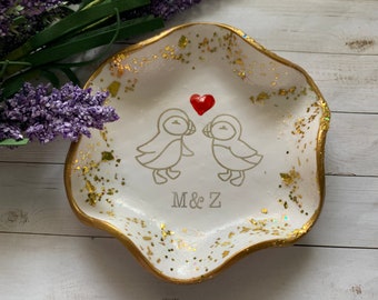 May include: White ceramic ring dish with a gold rim and gold glitter. Two stylized birds are facing each other with a red heart between them. The dish is personalized with the initials "M & Z".