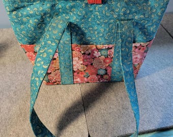 Bolso de mano para mujer en tejido estampado verde y rojo con múltiples bolsillos interiores y exteriores.