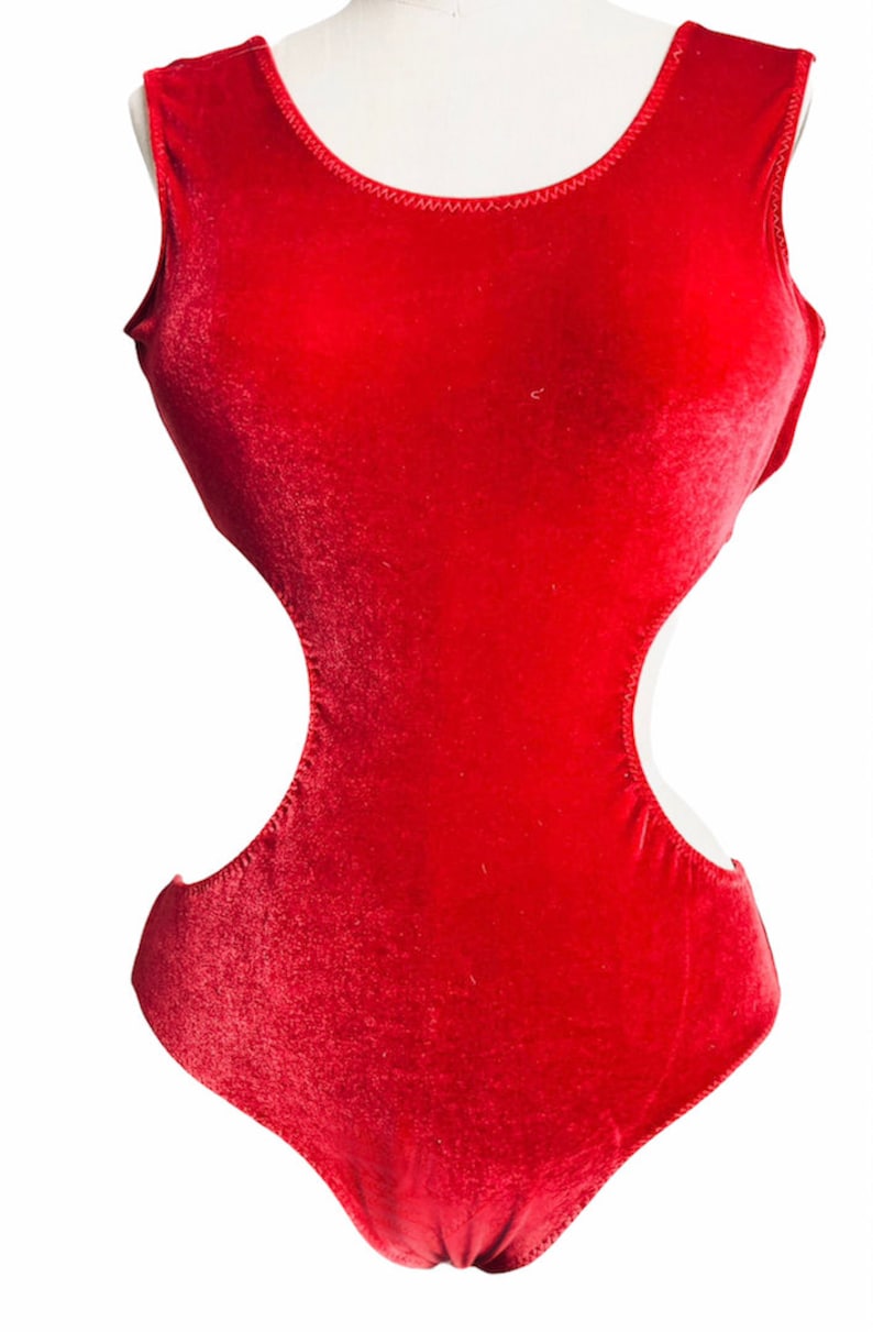 K&ouml;nnte beinhalten: Ein roter Samt-Bodysuit mit Rundhalsausschnitt und Ausschnitten an den Seiten.