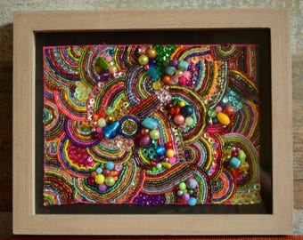 Multicoloured glimmering bead embroidery wall decoration in a frame.