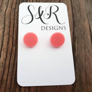 May include: A pair of pink round stud earrings on a white card with the text "S&R Designs".