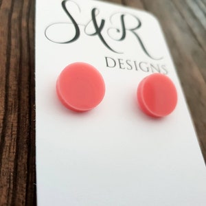 May include: A pair of pink round stud earrings on a white card with the text "S&R Designs".
