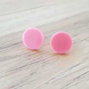 May include: A pair of pink round stud earrings.