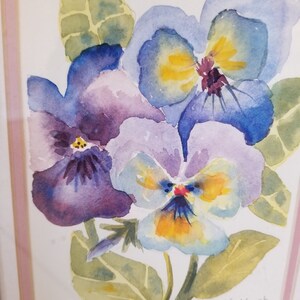 May include: Watercolour painting of three purple, blue and yellow pansies with green leaves. The painting is signed "Salleky 96".
