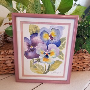 May include: Framed watercolour painting of purple and yellow pansies with green leaves. The painting is signed "Sally K. '96".