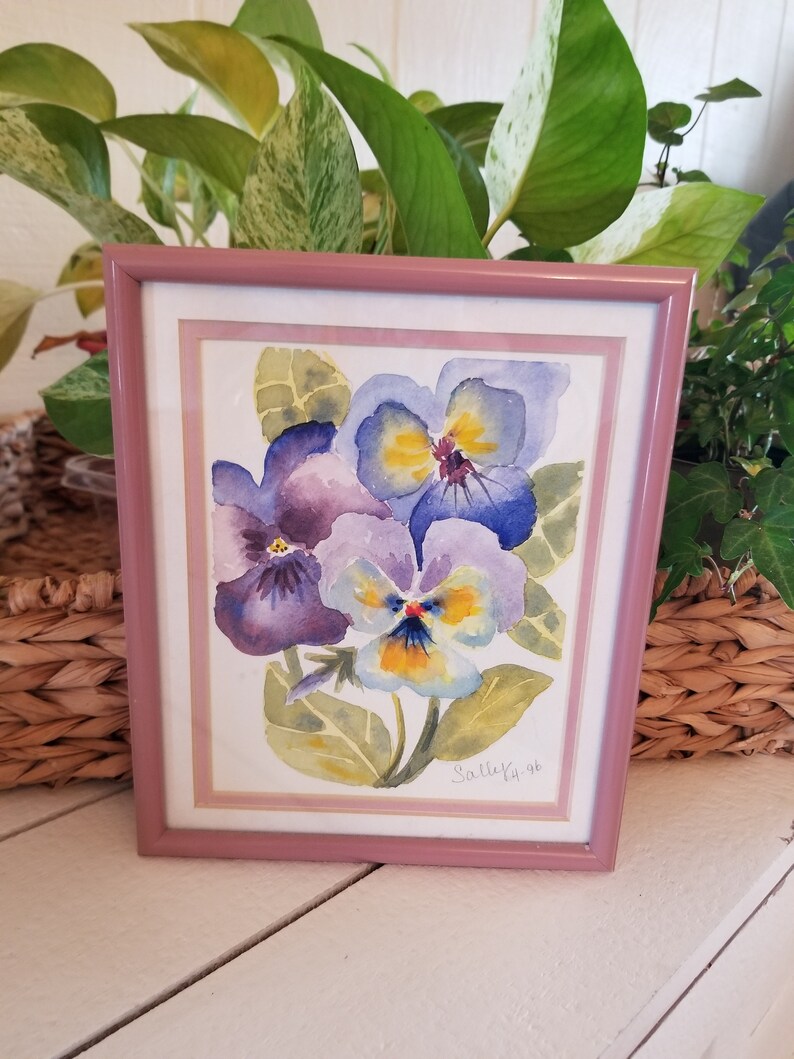 May include: Framed watercolour painting of purple and yellow pansies with green leaves. The painting is signed "Sally K. '96".