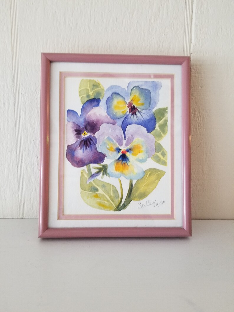 May include: A framed watercolour painting of three purple, blue, and yellow pansies with green leaves. The painting is signed "Sally K 96".