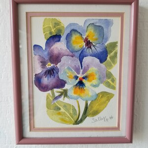 May include: A framed watercolour painting of three purple, blue, and yellow pansies with green leaves. The painting is signed "Sally '96".