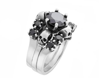 May include: A silver ring with a large black gemstone surrounded by smaller black gemstones and skull designs.