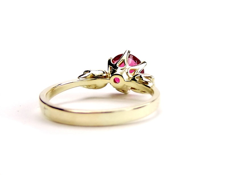 May include: A gold ring with a red gemstone set in a delicate, intricate design. The ring has a simple band and a detailed setting for the gemstone.