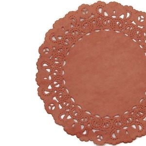 May include: A round, red paper doily with a delicate lace pattern. The doily is perfect for adding a touch of elegance to any occasion.