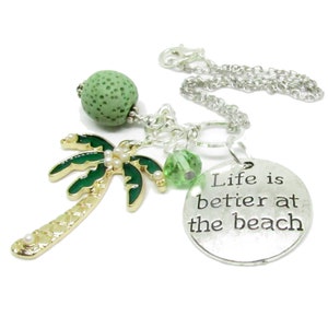 May include: A silver chain necklace with a green palm tree charm, a green lava bead, a green crystal bead, and a silver charm with the text "Life is better at the beach".