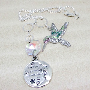 May include: Silver necklace with a hummingbird charm, a crystal charm, and a moon charm with the text "I love you to the moon & back".