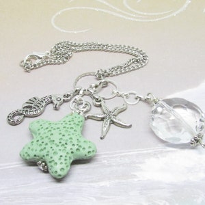 May include: A silver-toned necklace featuring ocean-themed charms. The charms include a seahorse, a starfish, and a light green starfish-shaped charm. A clear, faceted crystal bead hangs at the end of the chain. The necklace is designed with a lobster clasp.