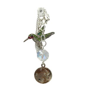 May include: Silver charm bracelet with a green and red jeweled hummingbird, a clear crystal, and a silver charm with the text "I love you to the moon & back".