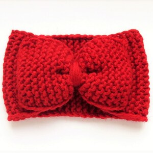 May include: A red knitted headband with a large bow in the center.