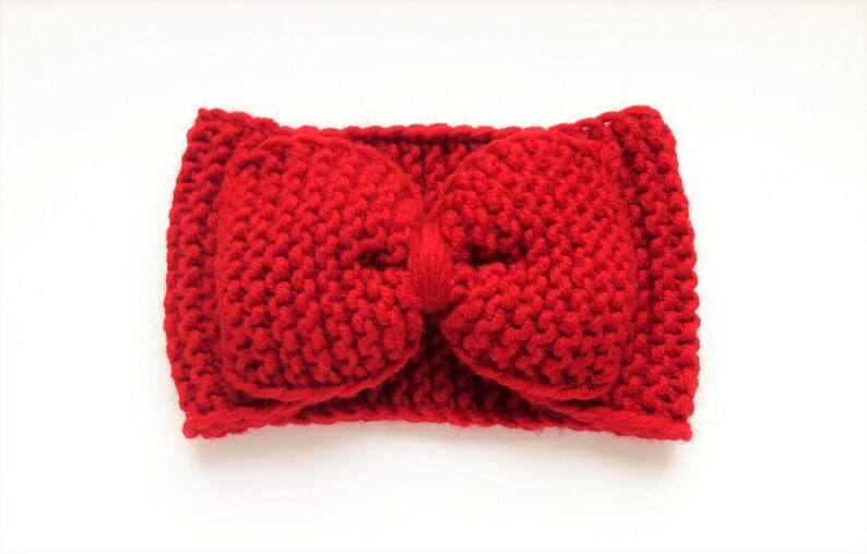 May include: A red knitted headband with a large bow in the center.