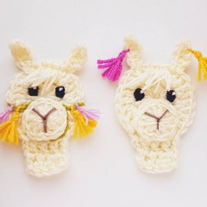 May include: Two crocheted llama ornaments with yellow and pink yarn tassels. The llamas are white with black eyes and brown noses.