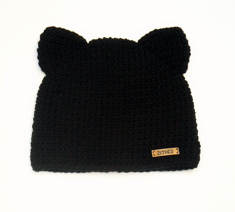 May include: Black knitted hat with ear flaps and a brown leather tag that says "27NICE".