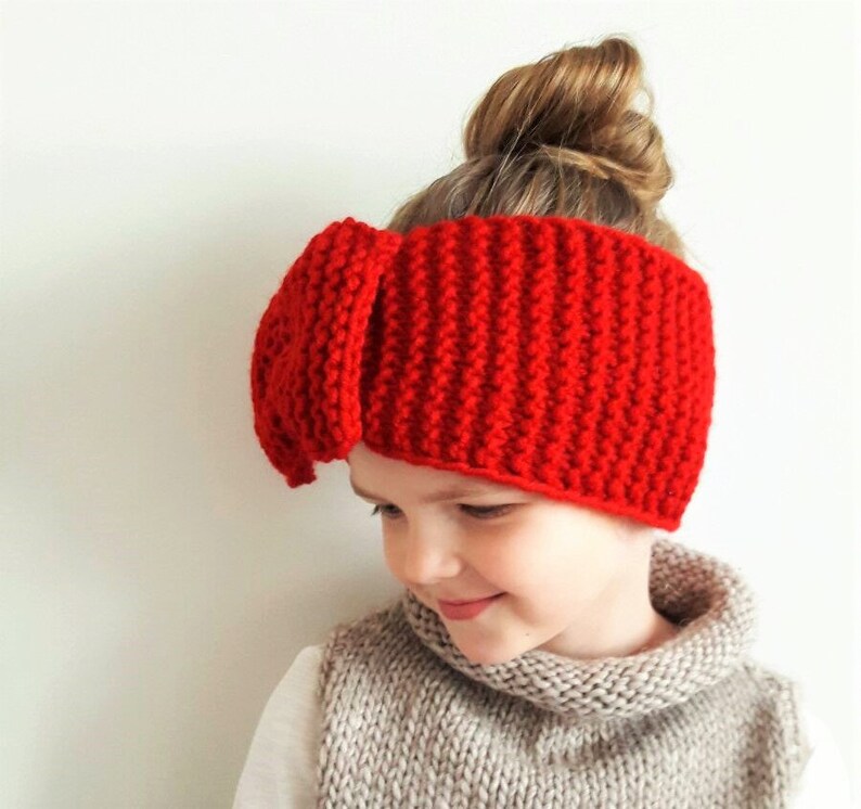 May include: Red knitted headband with a large bow on top. The headband is made of a soft, warm yarn and is perfect for keeping your ears warm in the winter.
