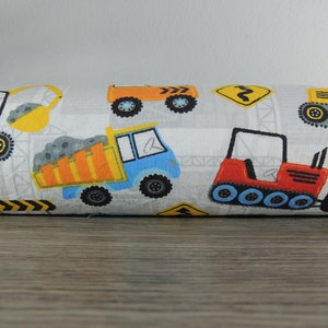 May include: A white fabric with a repeating pattern of construction vehicles. The vehicles are yellow, orange, red, and blue. There are also yellow and black warning signs.