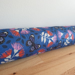 May include: A blue doorstop with a floral and butterfly pattern. The pattern features pink and red flowers, white stems, and blue butterflies.