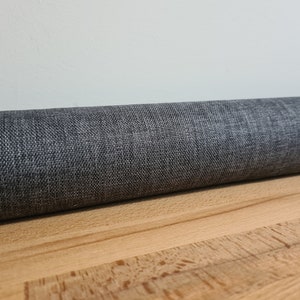 May include: A rolled up gray fabric with a textured surface.