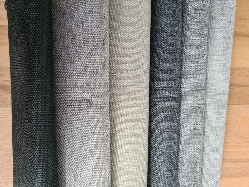 May include: Close-up of six fabric swatches in various shades of gray, from black to light gray. The fabric has a textured weave.