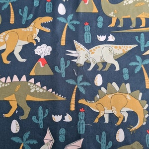 Puede incluir: Una tela azul con un patrón repetido de dinosaurios, palmeras y volcanes. Los dinosaurios son de varios colores, incluyendo verde, marrón y amarillo. La tela es perfecta para proyectos de manualidades, como colchas, almohadas y bolsos.