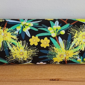 Op de afbeelding: Zwarte stof met een bloemenpatroon met gele en groene bloemen op een zwarte achtergrond.