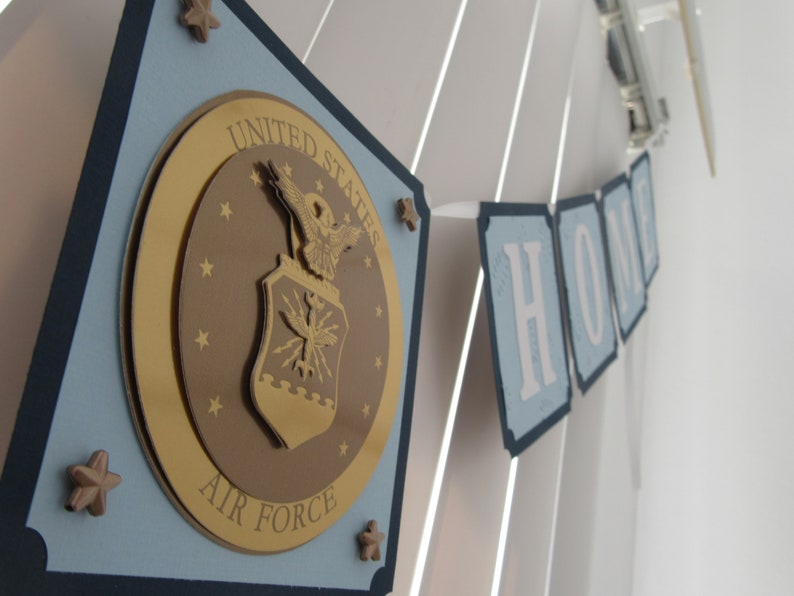 May include: A blue and gold banner with the United States Air Force emblem and the word "HOME" in white letters.