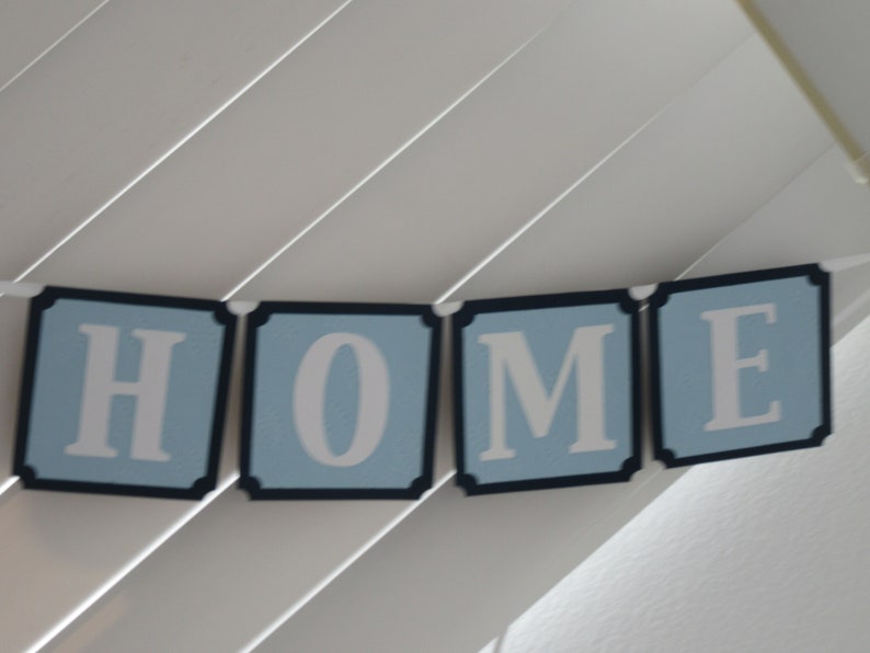 May include: A blue and white banner with the word "HOME" spelled out in white letters on a light blue background. Each letter is on a separate banner section with a black border.