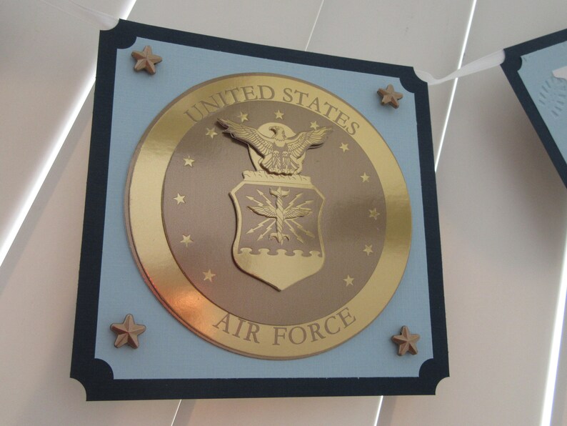 May include: A blue and gold United States Air Force banner with a gold eagle and shield emblem. The banner has a navy blue border and gold stars.