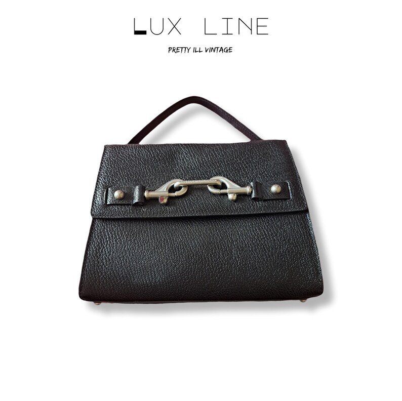 Puede incluir: Bolso de mano de cuero negro con cierre de solapa y cierre plateado. El bolso tiene un asa corta. El texto "LUX LINE" y "PRETTY ILL VINTAGE" se encuentra en la parte superior de la imagen.