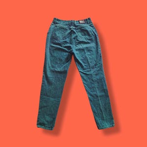 May include: Dark teal high-waisted jeans with a straight leg. The jeans have a classic five-pocket design and a "WAVE" label on the back waistband. The denim has a slightly faded appearance, suggesting a vintage style.