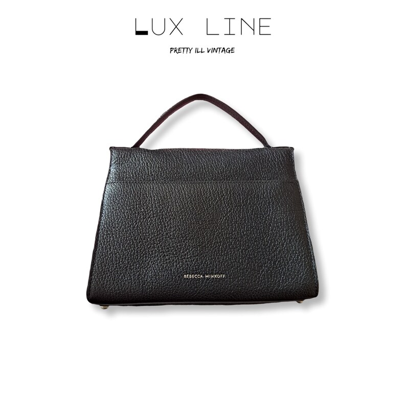 Puede incluir: Bolso de mano de cuero negro con asa superior. El bolso tiene una superficie texturizada y forma rectangular. El nombre de la marca "REBECCA MINKOFF" es visible en la parte delantera. El texto "LUX LINE" y "PRETTY ILL VINTAGE" est&aacute;n en la parte superior.