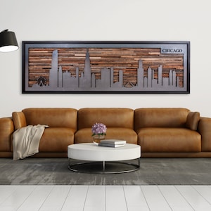 Peut inclure: Un canap&eacute; en cuir marron avec un plaid est plac&eacute; devant une &oelig;uvre d'art murale en bois et m&eacute;tal repr&eacute;sentant l'horizon de Chicago. L'&oelig;uvre d'art est encadr&eacute;e de noir et porte le mot "CHICAGO" dans le coin sup&eacute;rieur droit.